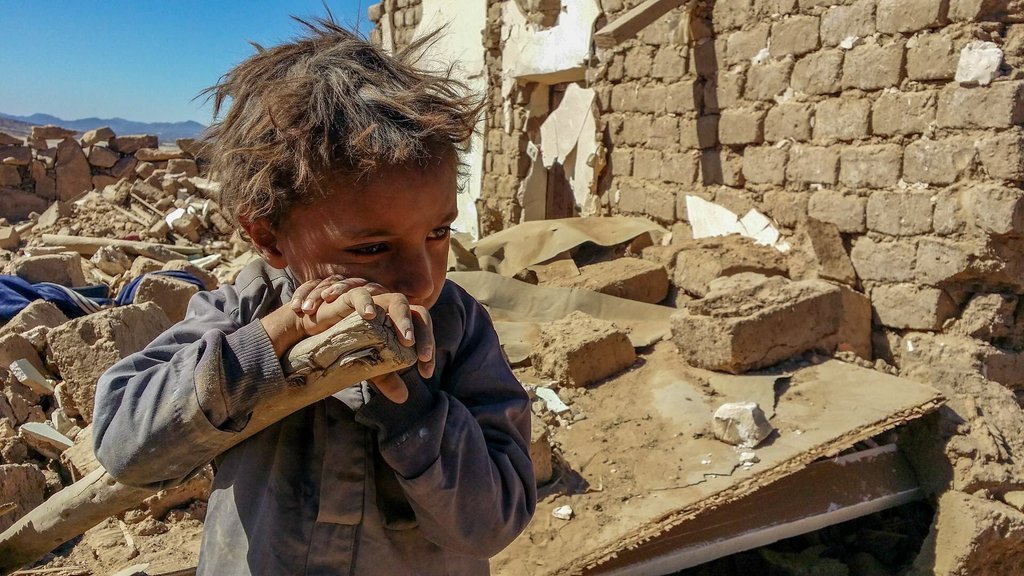 Child in war-torn region surrounded by rubble